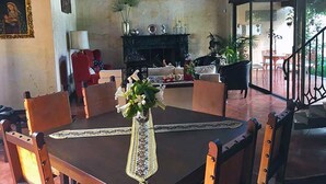 A dining area with a table set for four, surrounded by wooden chairs. A vase with flowers is on the table.