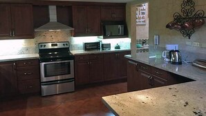 A kitchen with dark wooden cabinets, stainless steel appliances, a microwave, and a decorative wall piece.