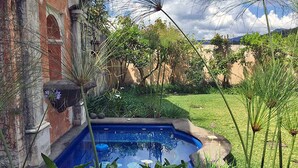 A swimming pool surrounded by lush greenery and a rustic building.