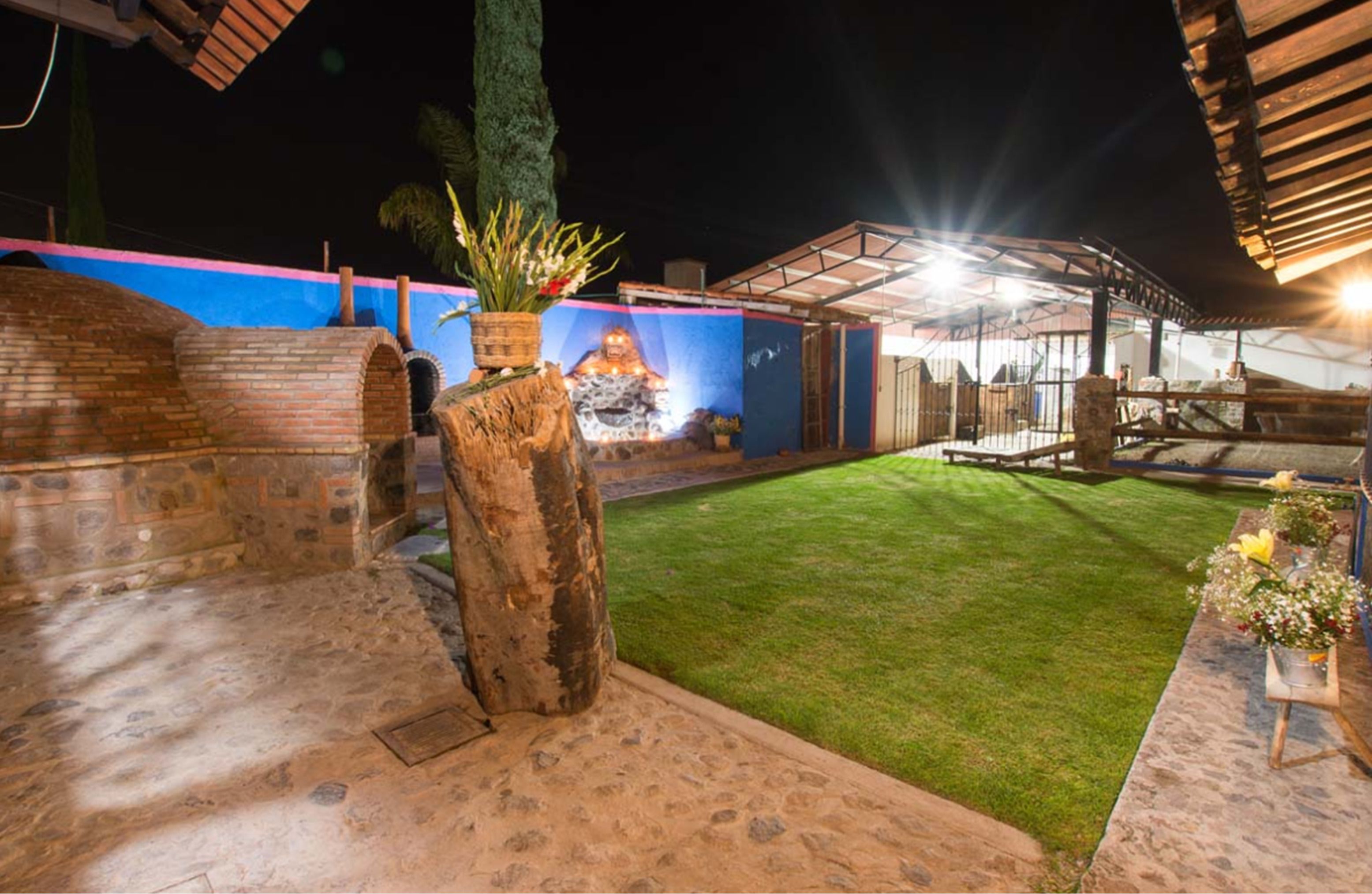 An outdoor patio area with a brick wall, a stone pillar, and a grassy lawn.