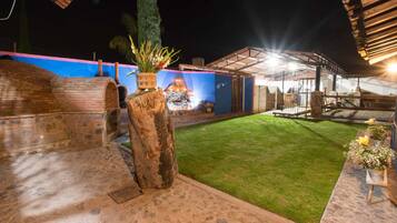 An outdoor patio area with a brick wall, a stone pillar, and a grassy lawn.