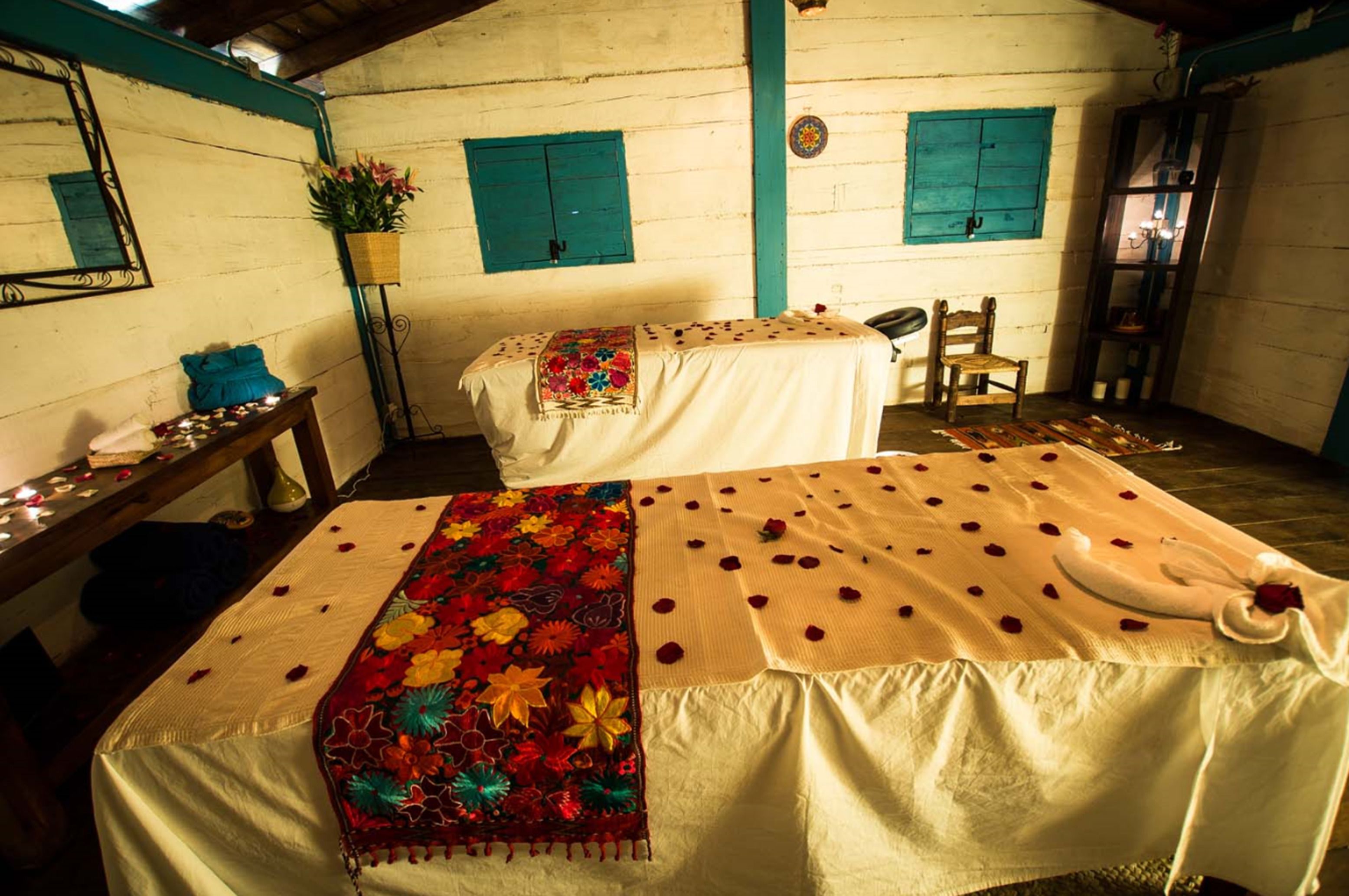 A room with a bed, a chair, a table with candles, and a mirror.