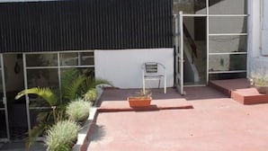 A building with a black awning, a chair, and potted plants. - Casa Zapopan Hotel (Zapopan)