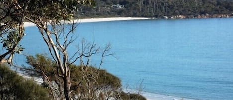 A coastal landscape with a sandy beach and clear blue water.