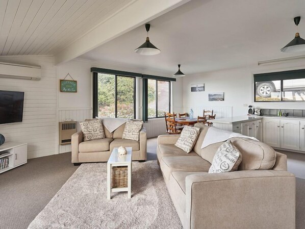 A spacious living room with a large window, a dining area, and a kitchen.