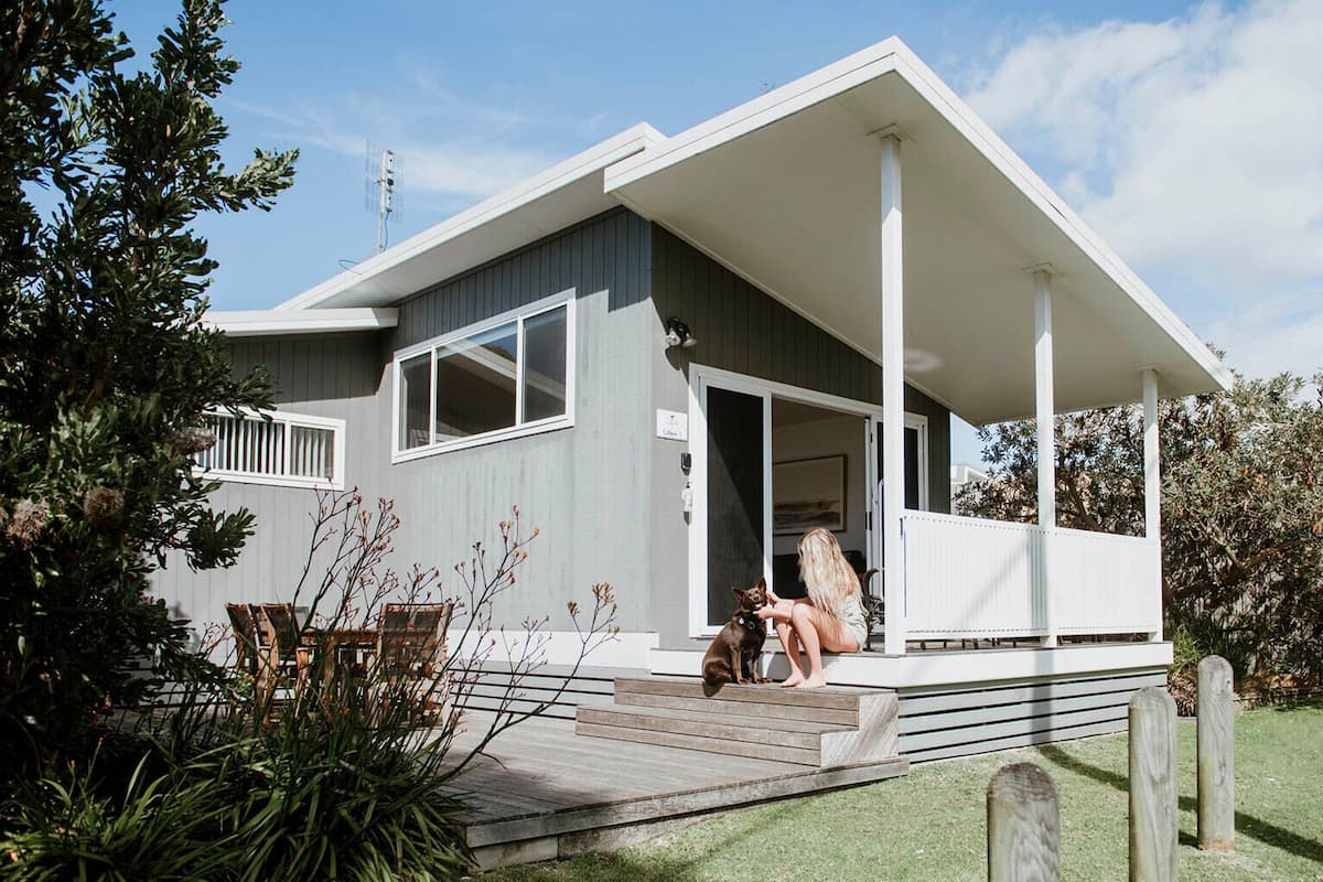 A modern house with a covered porch, a wooden deck, and a well-maintained garden.