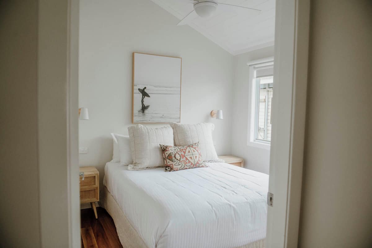 A bedroom with a large bed, two bedside tables, a wall-mounted artwork, and a window.