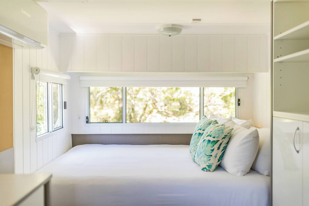 A bedroom with a bed, a window, and a ceiling light.