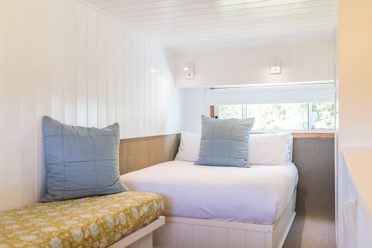 A bedroom with two beds, one with a patterned bedspread and the other with plain bedding.