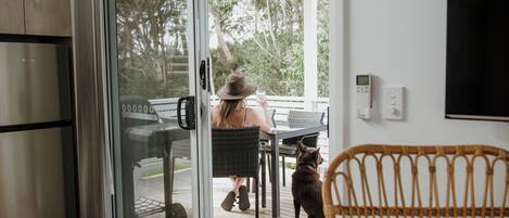 Een moderne keuken met een roestvrijstalen koelkast, een glazen deur naar een terras en een rieten stoel.
