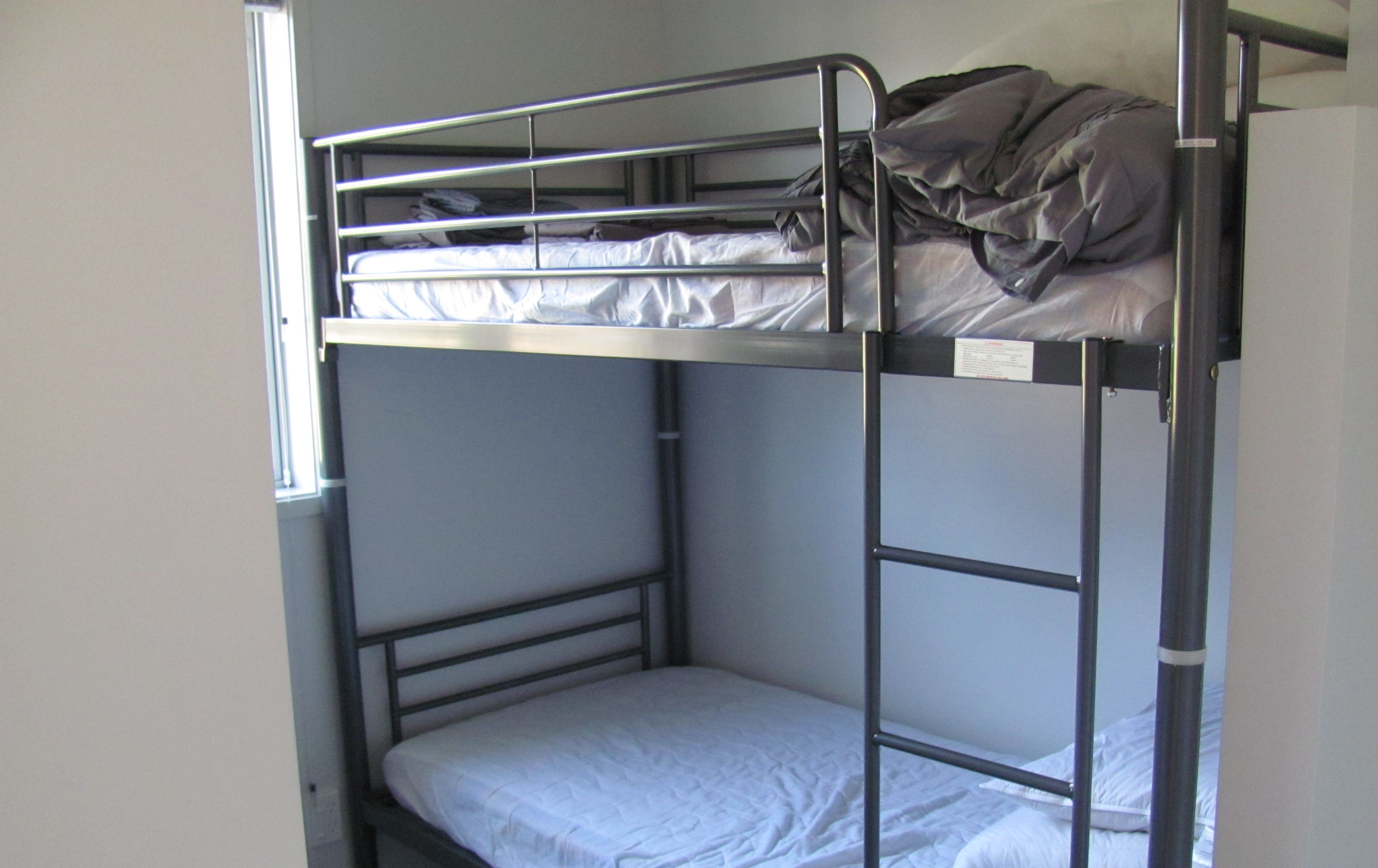 A bunk bed with a metal frame and white bedding.