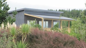 A modern house with a flat roof, large windows, and a wooden deck.