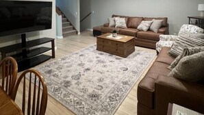 Un salon avec un canapé, une table basse, un téléviseur et un escalier.