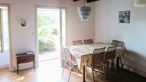A dining area with a table and chairs, a bench, a hanging light fixture, and a door leading outside.