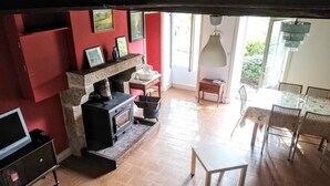A cozy living room with a fireplace, a TV, and a dining area with chairs and a table.