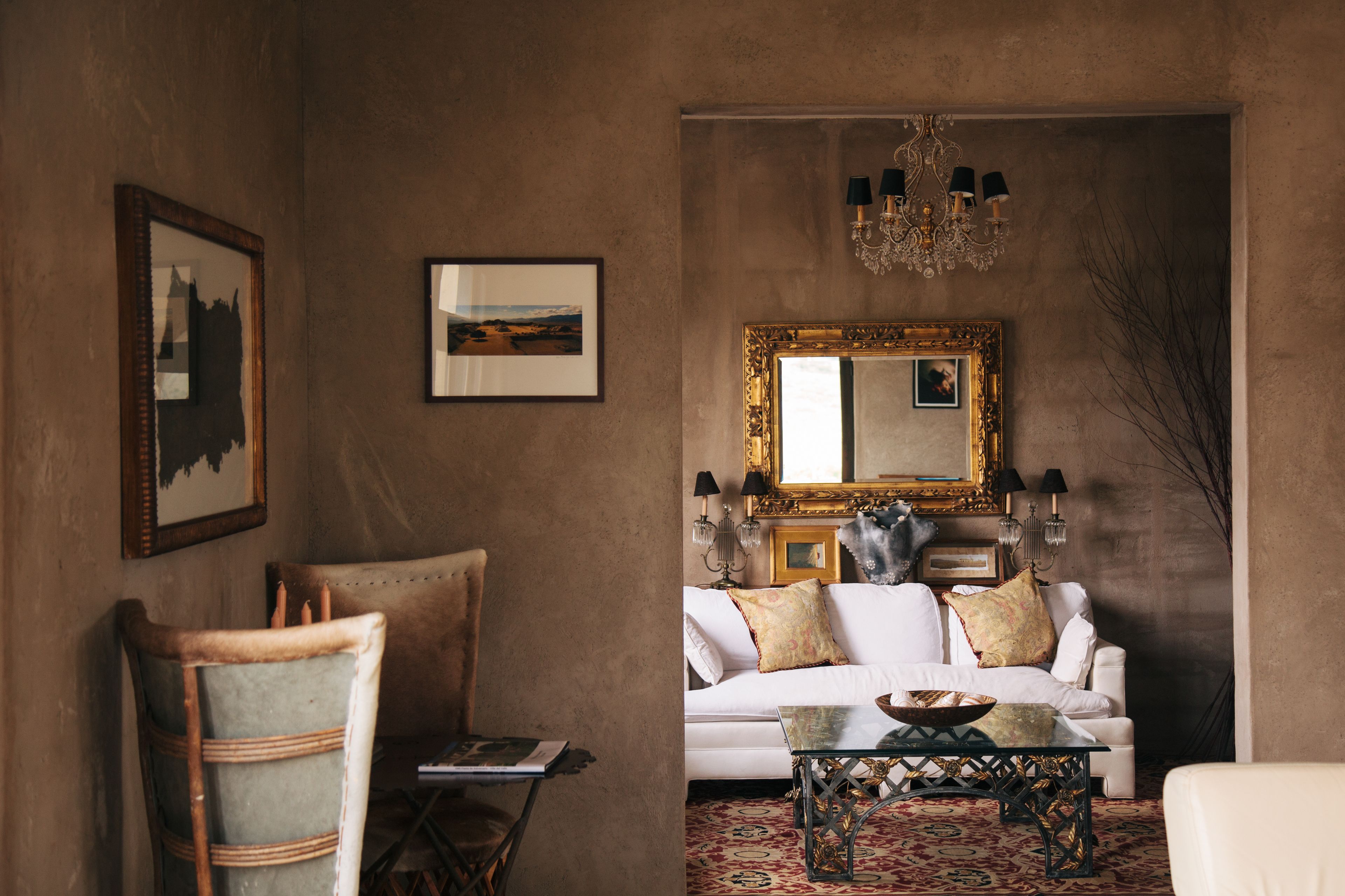 A cozy living room with a white sofa, a glass coffee table, and a large mirror on the wall.