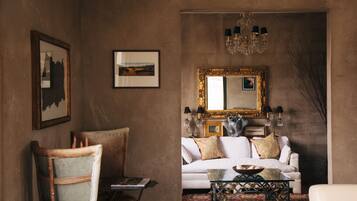 A cozy living room with a white sofa, a glass coffee table, and a large mirror on the wall.
