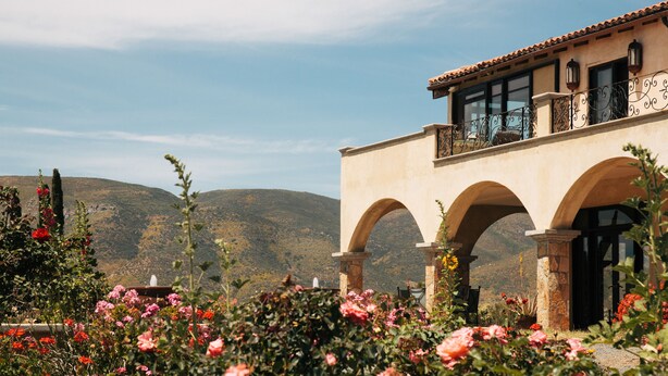 Un edificio con arcos y un balcón con vistas a un paisaje montañoso.