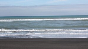 A beach with waves approaching the shore. - Comfortable Beach-Front House (Turakina Beach)