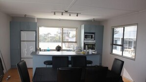 A modern kitchen with a dining area, featuring a central island, a microwave, and a refrigerator. - Comfortable Beach-Front House (Turakina Beach)