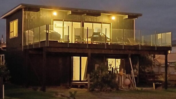 A two-story house with a balcony and a covered patio area. - Comfortable Beach-Front House (Turakina Beach)