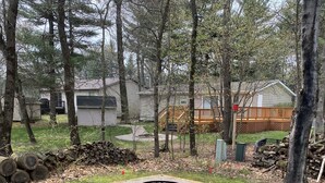 A backyard with a fire pit, a wooden deck, and a house in the background. - Sunny Retreat at Springbrook Resort (Wisconsin Dells)