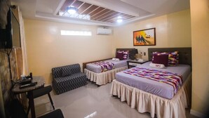 A room with two beds, a small table, a chair, and a ceiling with skylights. - Tops Lodging House (San Juan)