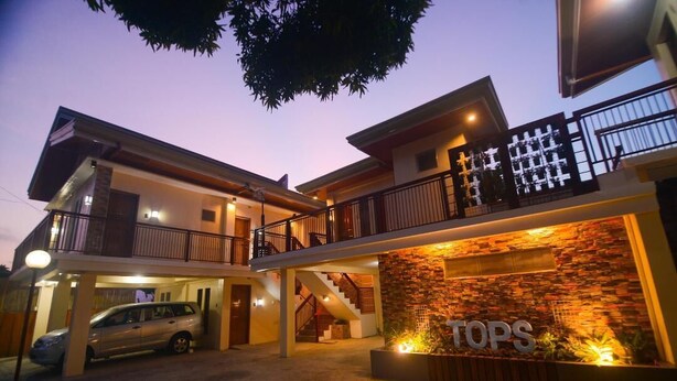 A two-story building with a car parked in front, a staircase leading to the upper level, and a sign that reads "TOPS". - Tops Lodging House (San Juan)