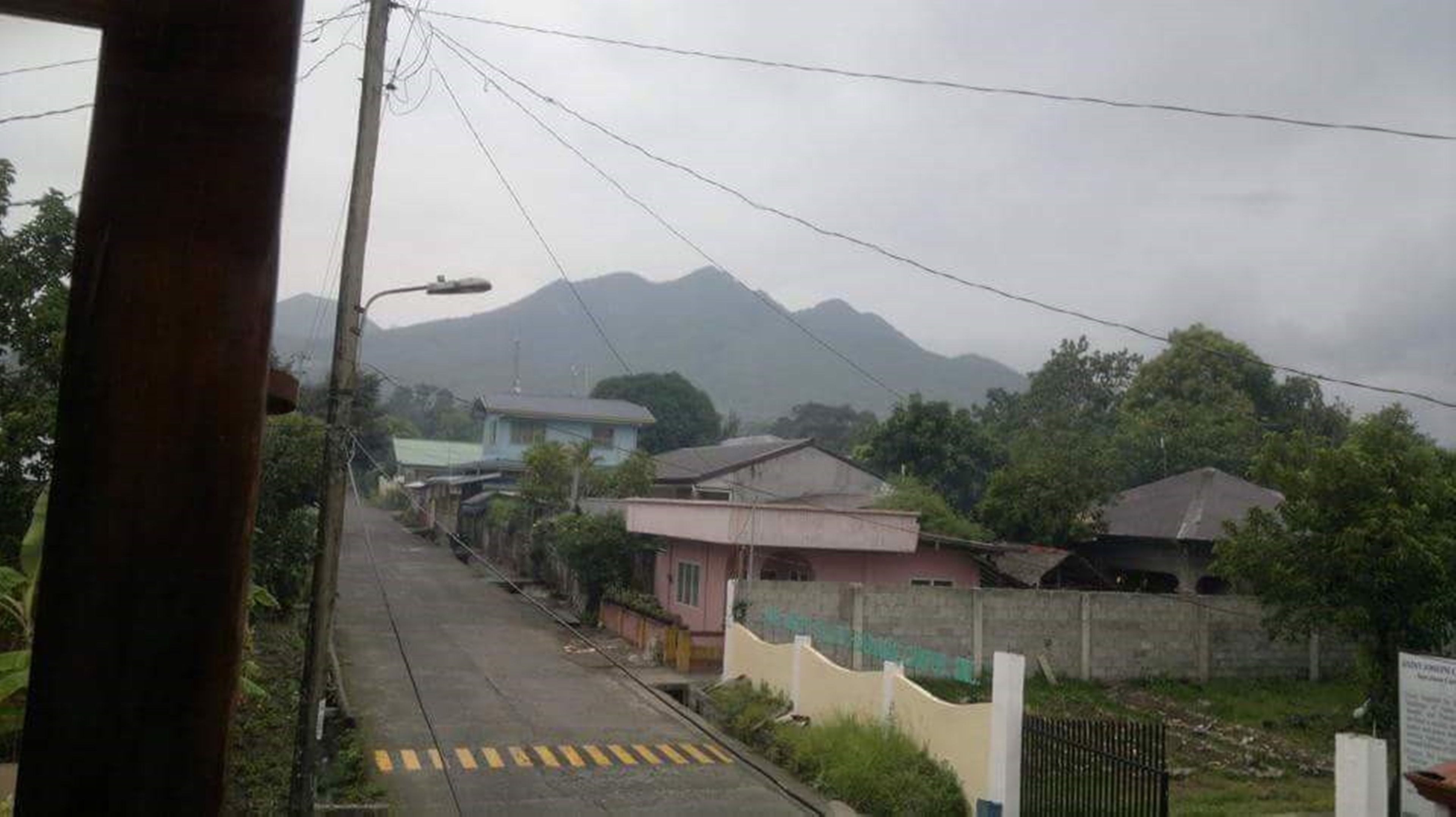 A residential street with houses, a clear road, and mountains in the background.