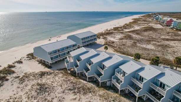 A beachfront hotel with multiple blue buildings, each featuring balconies and direct ocean views.