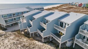 A beachfront property with multiple blue buildings featuring balconies and a sandy beach in the background.