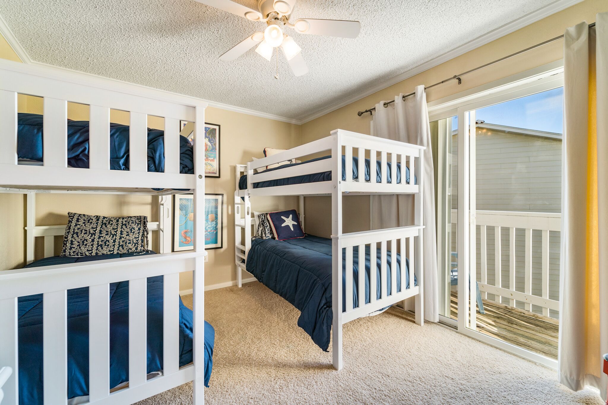A bedroom with two bunk beds, a ceiling fan, and a large sliding glass door leading to a balcony.