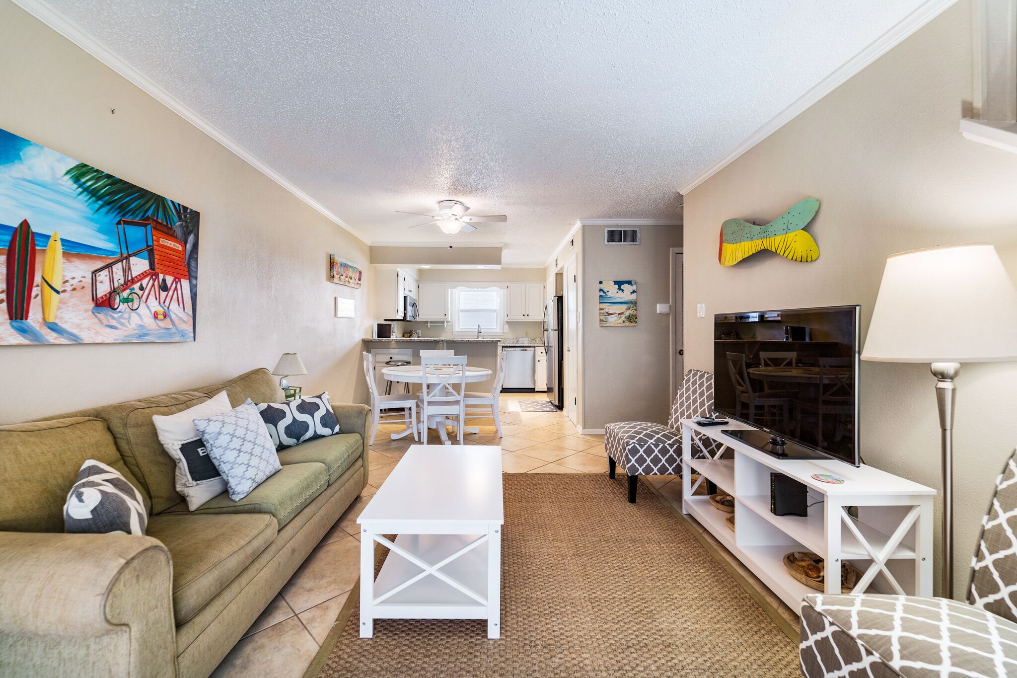 A living room with a sofa, coffee table, TV, and a dining area with chairs and a table.
