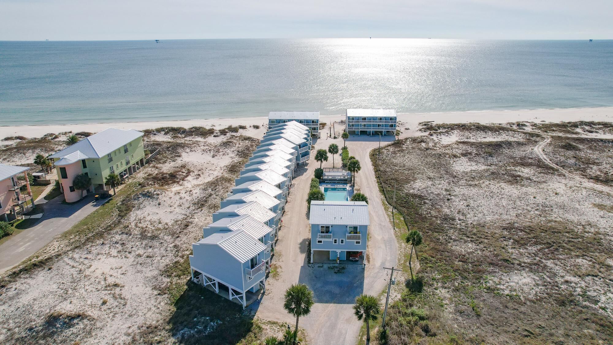 Ett flygbildsbild av ett hotell vid kusten med flera byggnader, en swimmingpool och en strand.