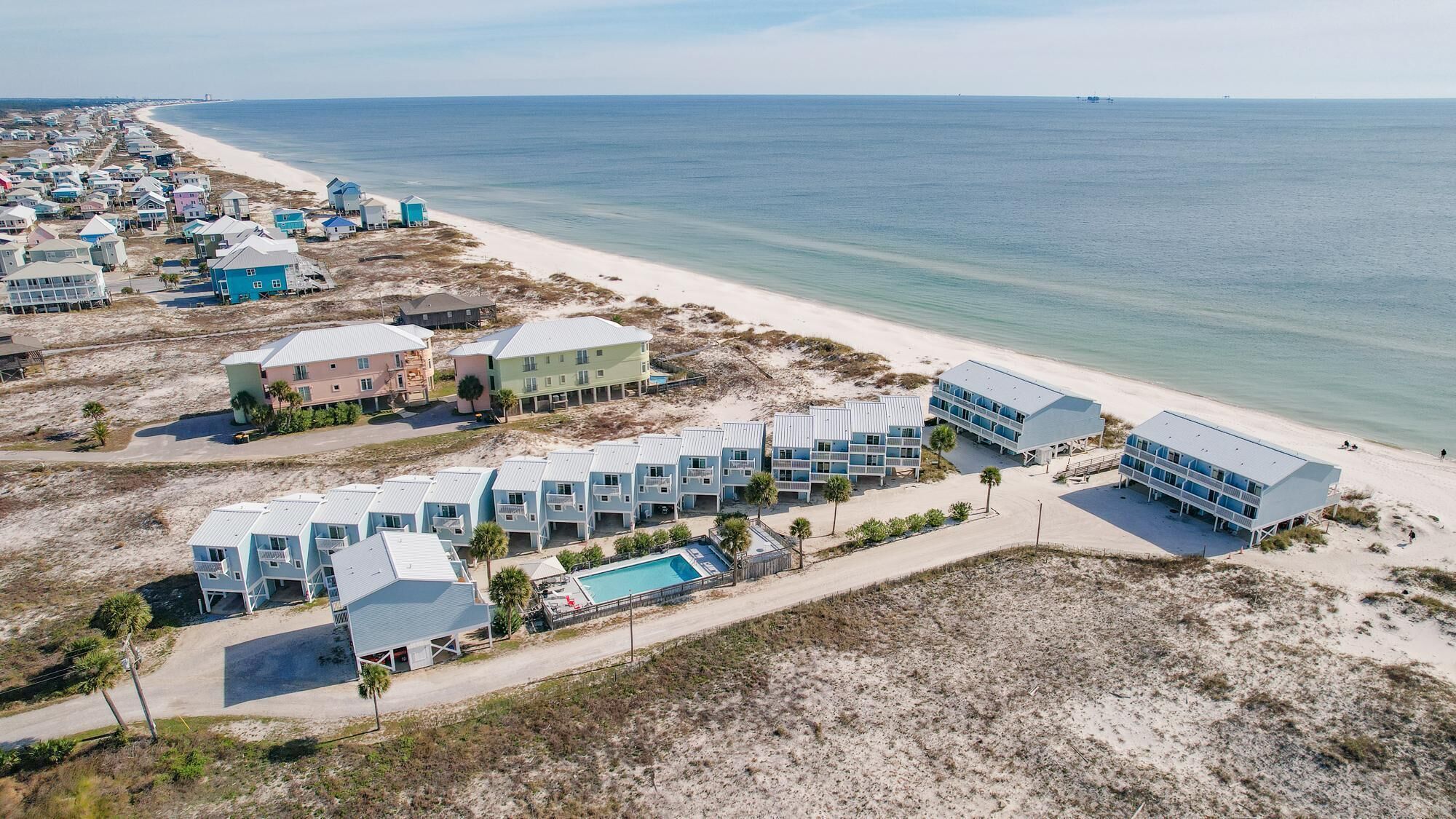 Ein Küstenhotel mit mehreren Gebäuden, einem Strand und freiem Blick auf den Ozean.