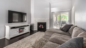A living room with a flat-screen TV, white entertainment unit, grey sofa, and a fireplace. - Picture Perfect Paradise Valley Condo (Paradise Valley)