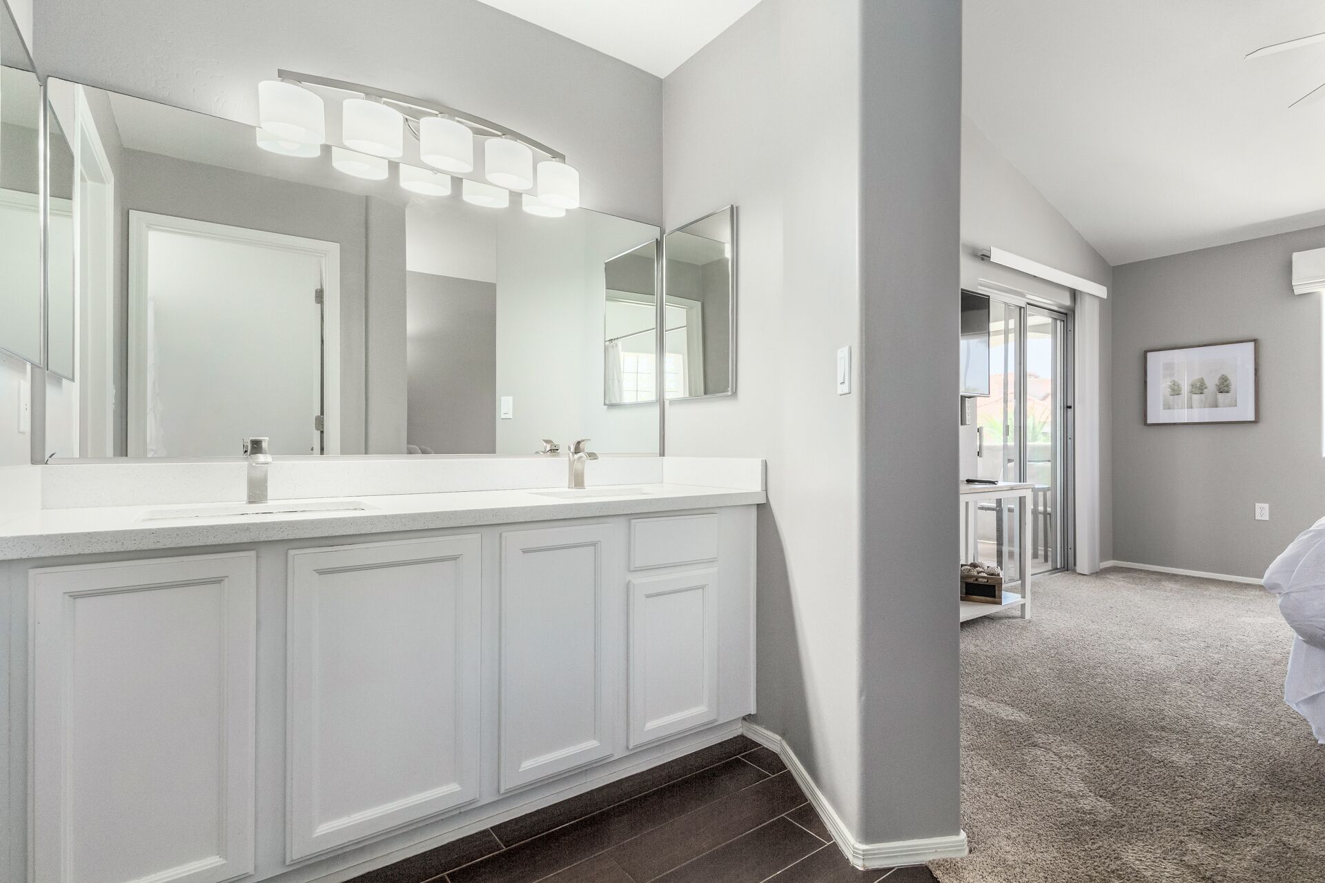 A modern bathroom with a large mirror, two sinks, and a lighted vanity.