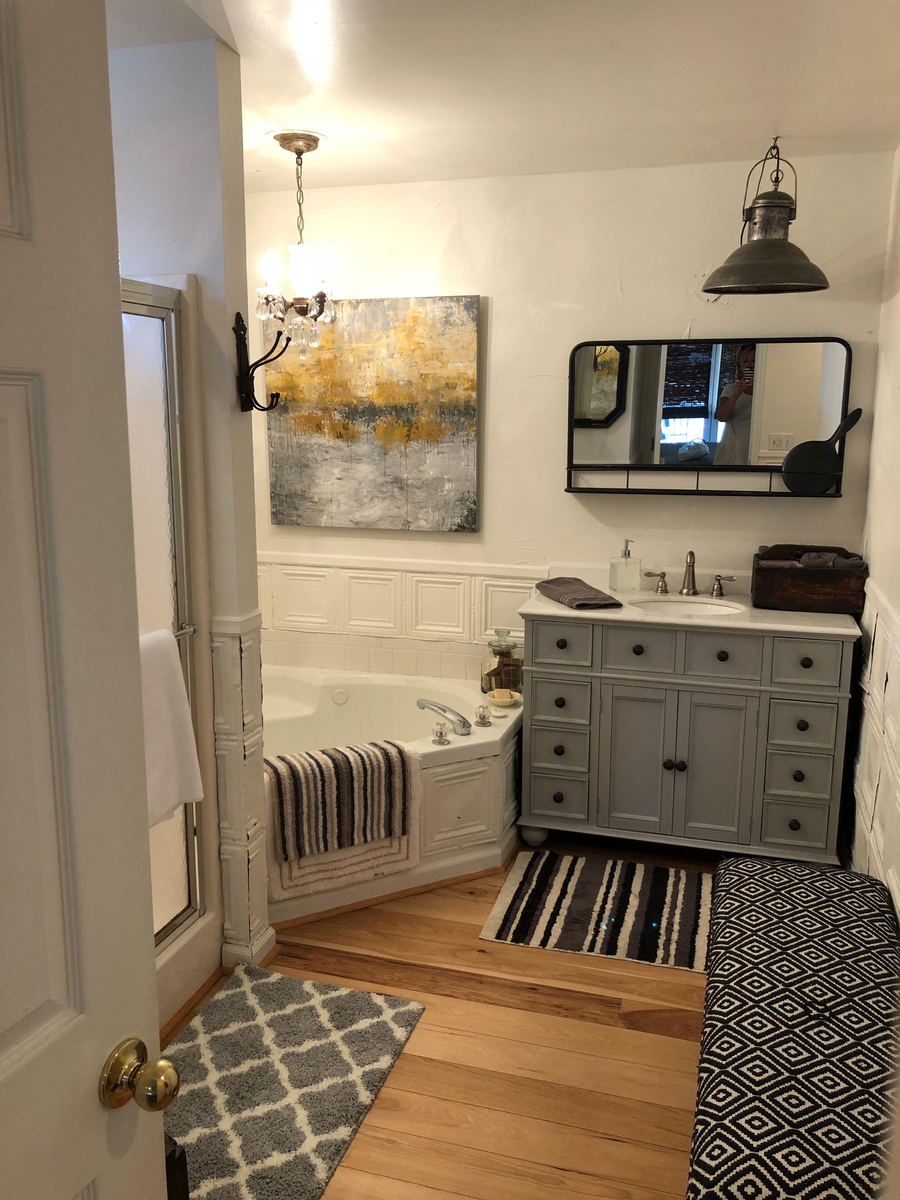 A bathroom with a bathtub, a vanity with a mirror, and a painting on the wall.
