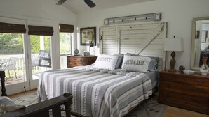 A bedroom with a bed, wooden dresser, and a window with blinds. - Cozy Waterfront Chalet with Great Dock (HIAWASSEE)