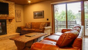 Un salon chaleureux avec une cheminée en pierre, un canapé en cuir et une table basse en bois.