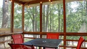 A covered outdoor seating area with a table and chairs, large windows, and string lights. - Arbor Dell 1 Block from Lake Delton (Wisconsin Dells)