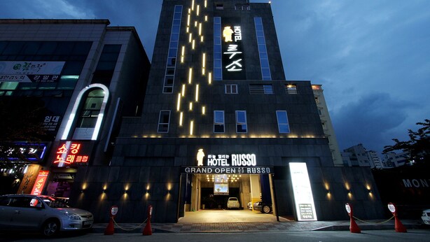 A hotel with a modern design, featuring a prominent entrance and signage indicating a grand opening. - Russo Hotel (Gangneung)