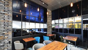A modern cafe with brick walls, large windows, and wooden tables and chairs. - Russo Hotel (Gangneung)