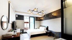 A modern hotel room with a large bed, a desk with a chair, a vanity with a mirror, and a bathroom with a bathtub and shower. - Russo Hotel (Gangneung)