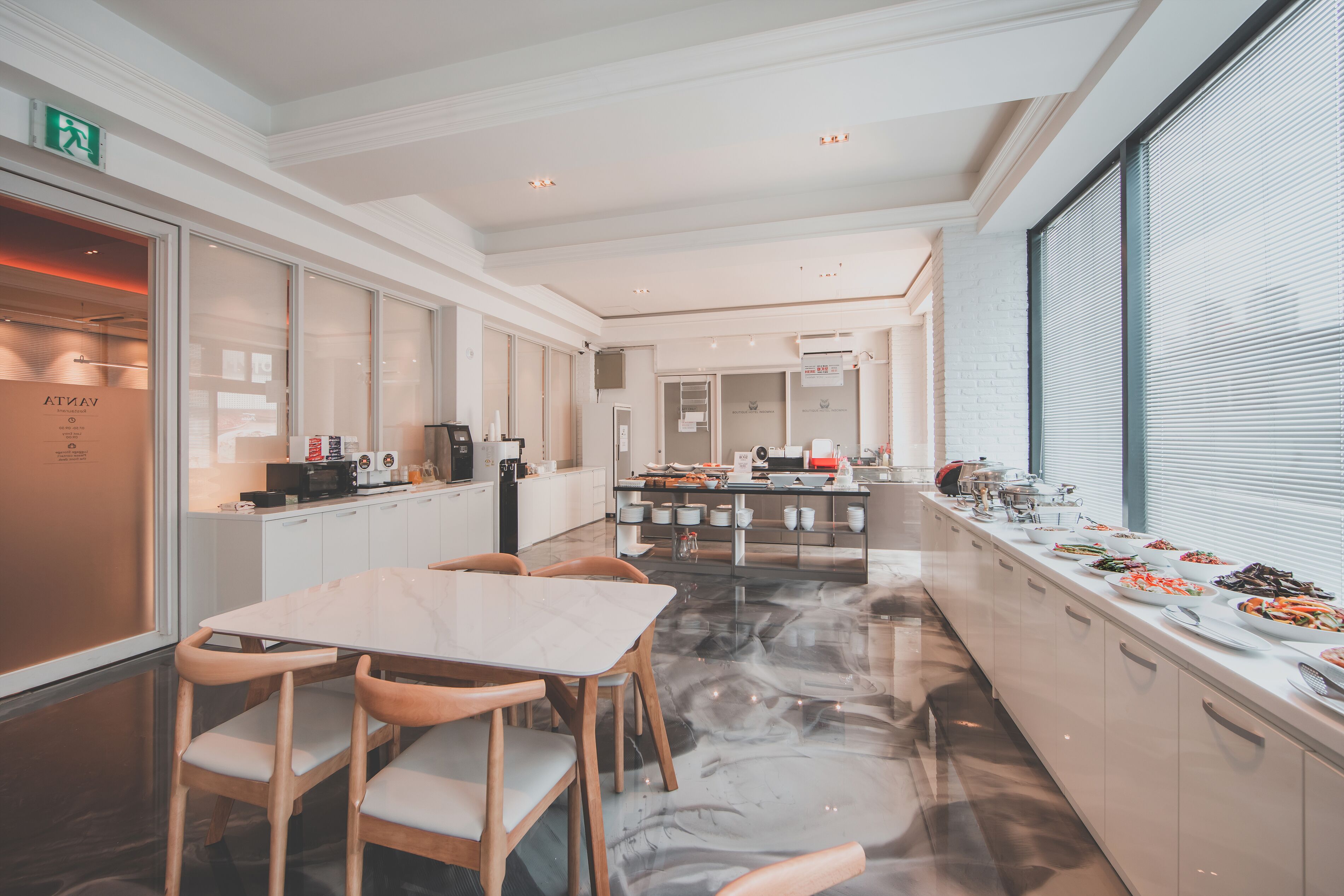 A modern kitchen with a marble floor, white cabinetry, and a buffet setup with various dishes.