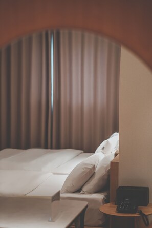 Habitación de hotel con cama, mesita de noche y teléfono.