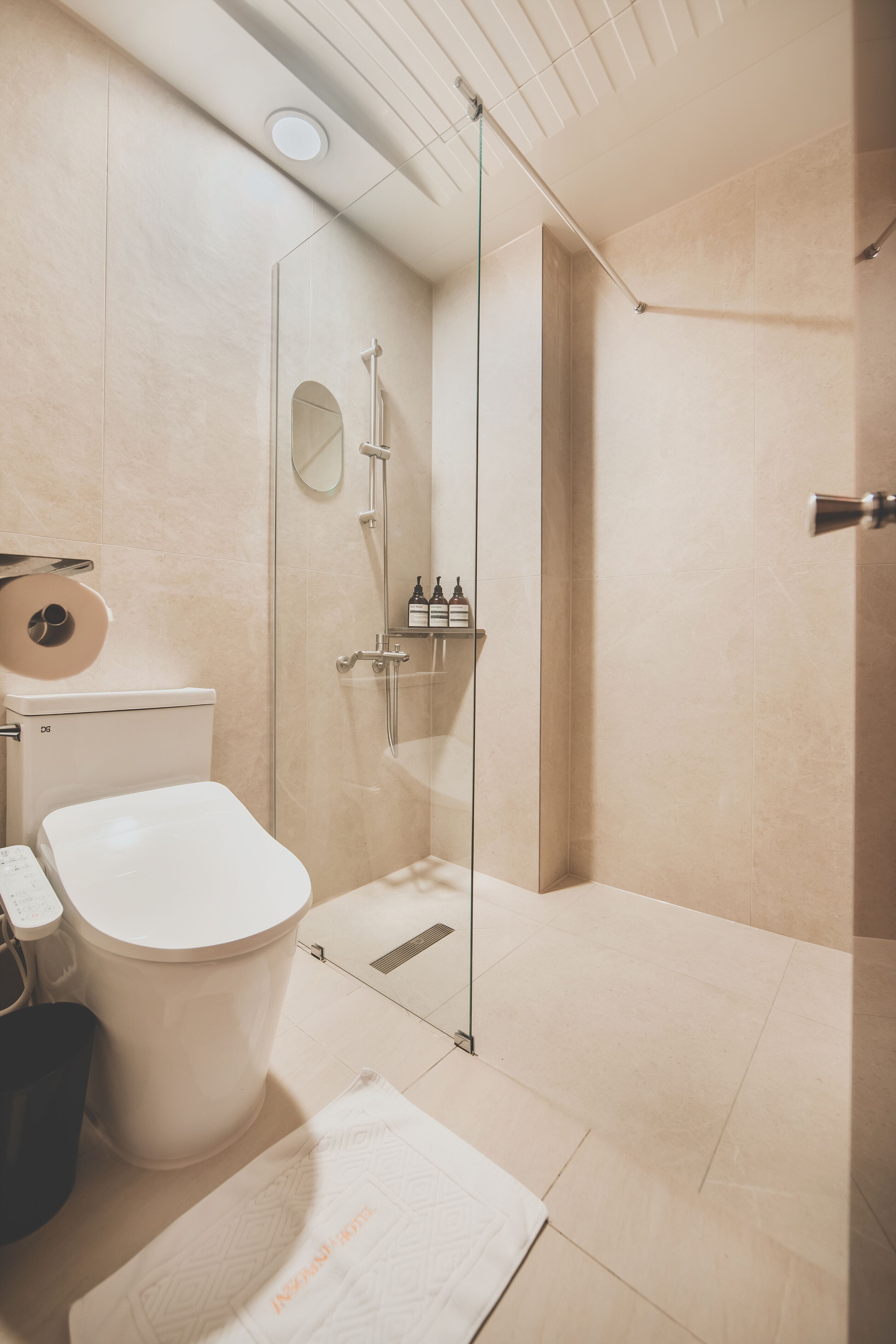 Ein modernes Badezimmer mit Toilette, einer gläsernen Dusche und einem Spiegel.