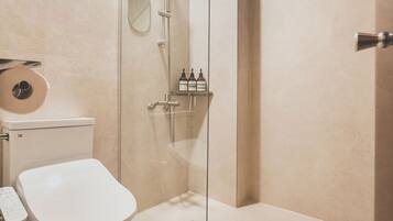 Ein modernes Badezimmer mit Toilette, einer gläsernen Dusche und einem Spiegel.