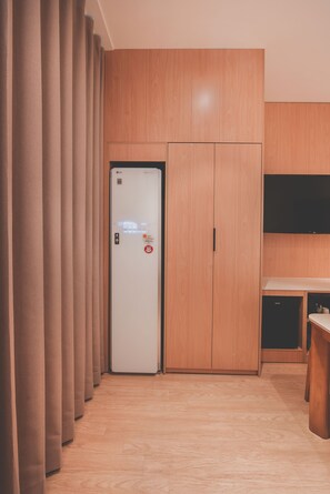 Ein Hotelzimmer mit Kleiderschrank, Flachbildfernseher und einer Küchenzeile.