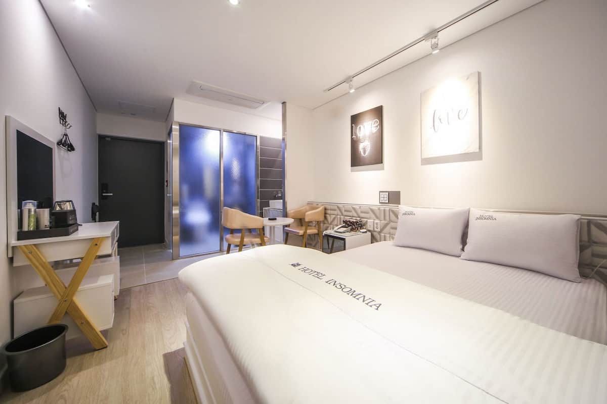 Una habitación de hotel moderna con cama, escritorio, silla y una pequeña mesa.